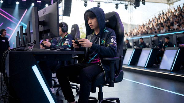 电竞赛事舞台上选手在电脑前进行比赛并配有舞台灯光的画面
